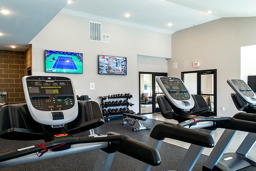 a gym with treadmills and a tv on the wall