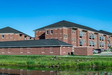 a large brick building with a pond in front of it