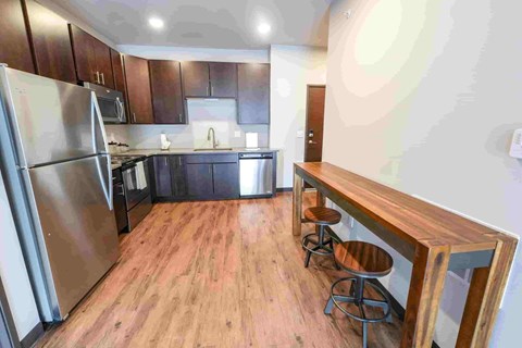 A kitchen with a refrigerator, microwave, oven, and sink.