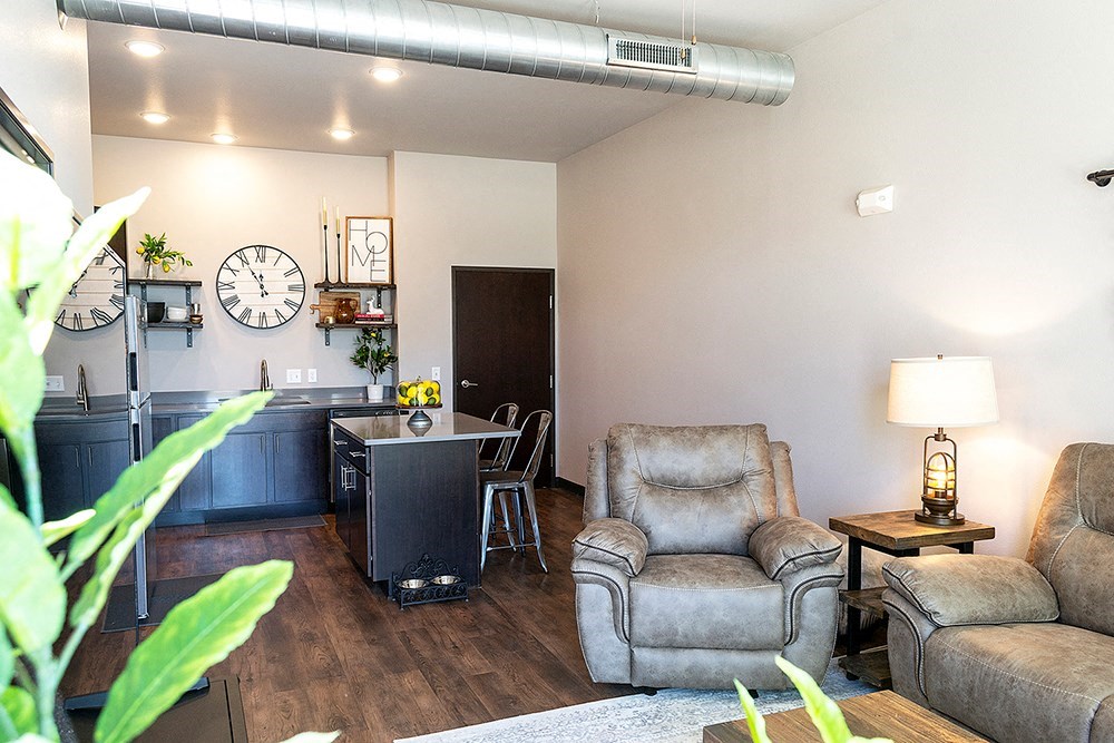 a living room and kitchen with a clock on the wall