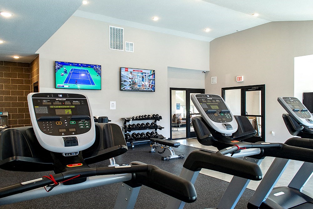 a gym with treadmills and a tv on the wall
