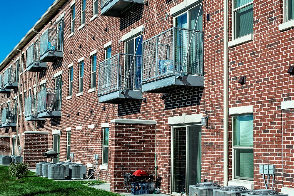 a brick apartment building with balconies and grass