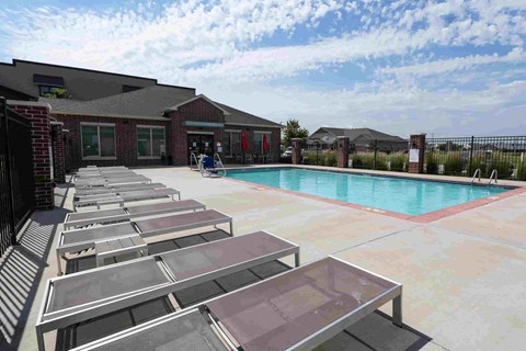 A pool with sun loungers in front of a building.