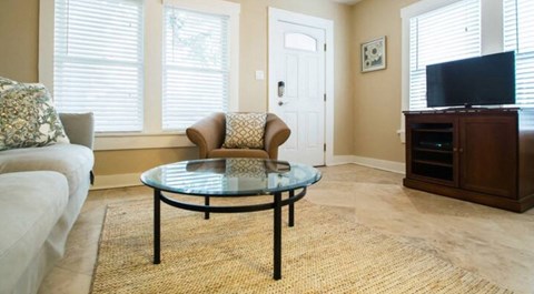 A living room with a glass table and a white couch.