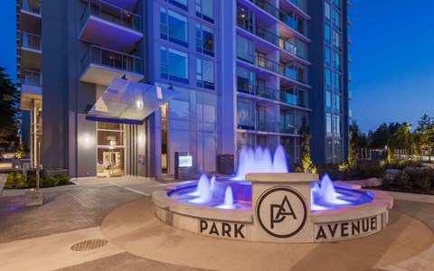 a fountain in front of an apartment building at night