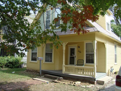 A yellow house with a mailbox on the front porch.