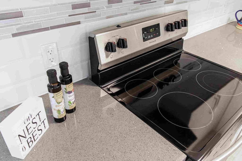 a stove in a kitchen next to a counter with two bottles of spices