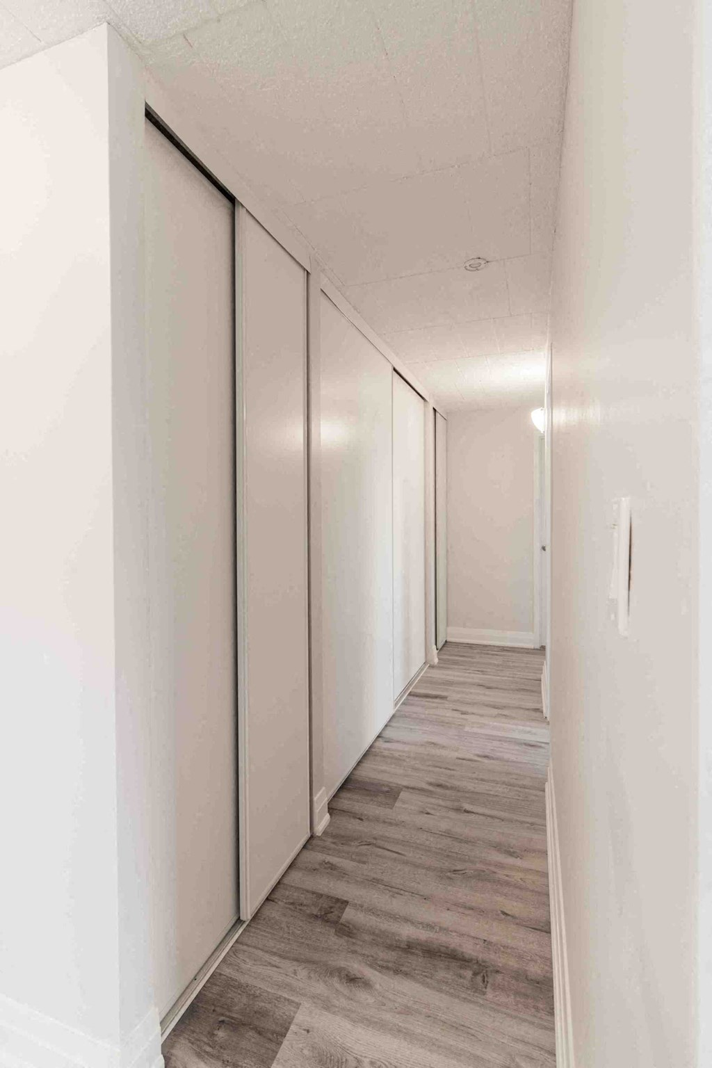 a long hallway with white cabinets and wood floors