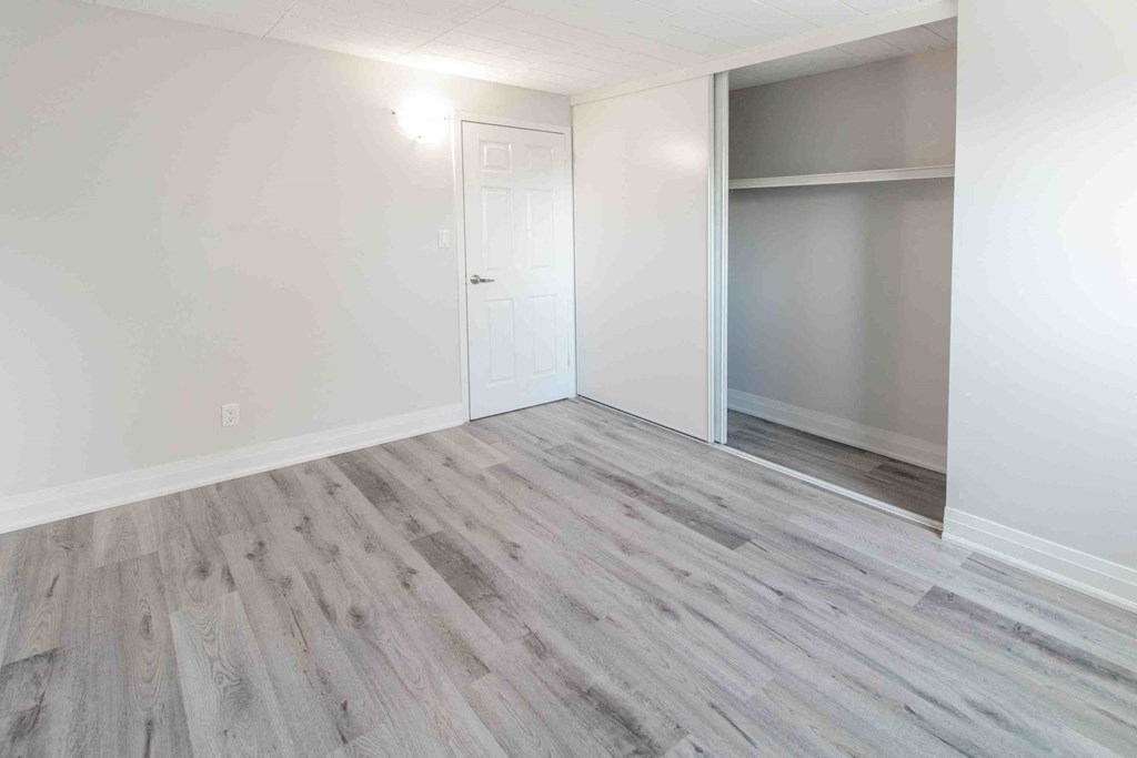 an empty room with wood flooring and a closet