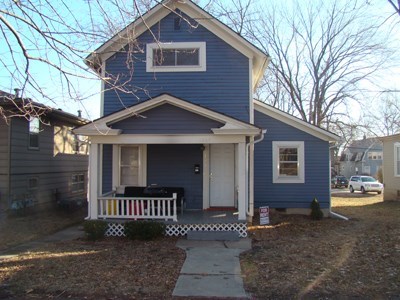 A blue house with a white door and a small porch.