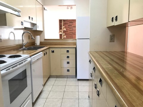 A kitchen with white appliances and wooden countertops.