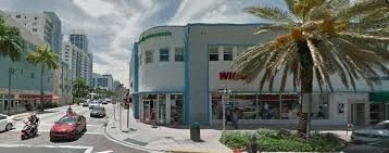 A street view with a palm tree and a building with a sign that says "Wil".