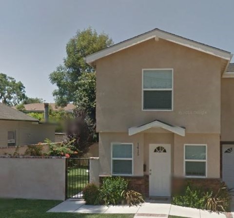 A beige house with a white door and windows.