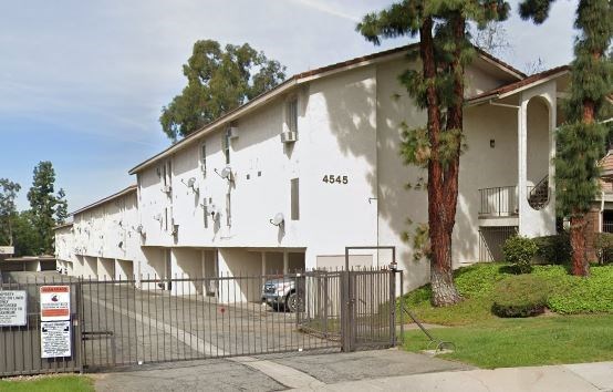 a white building with a fence and a tree