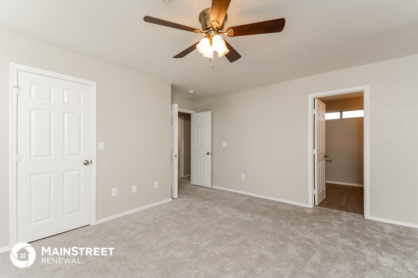 the spacious living room with ceiling fan and carpeting