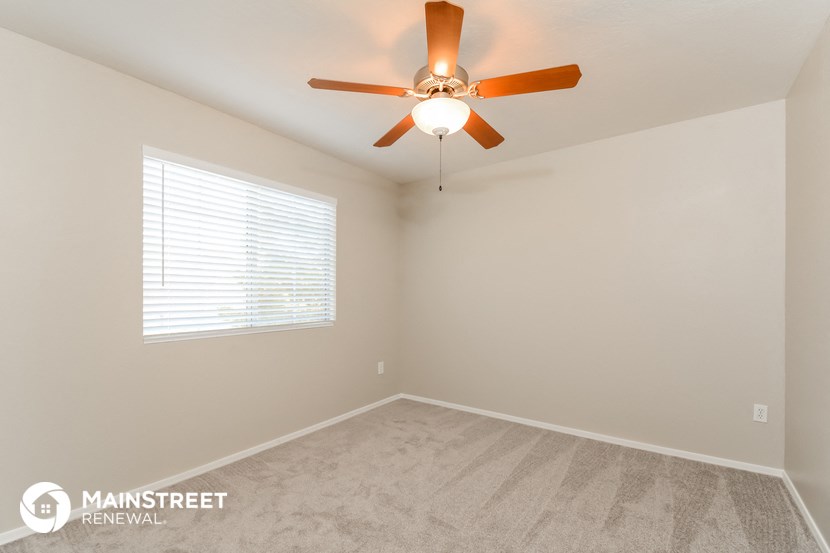 the spacious living room with ceiling fan and carpet