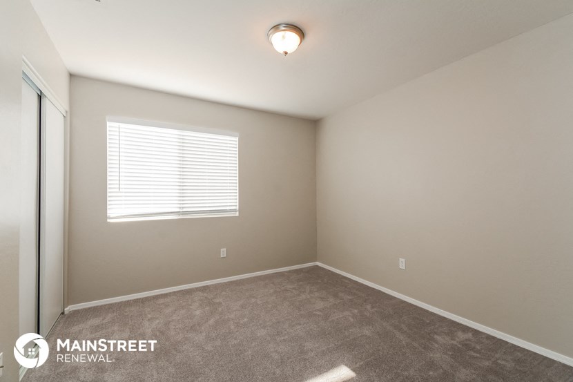 the spacious bedroom with carpeted flooring and a window