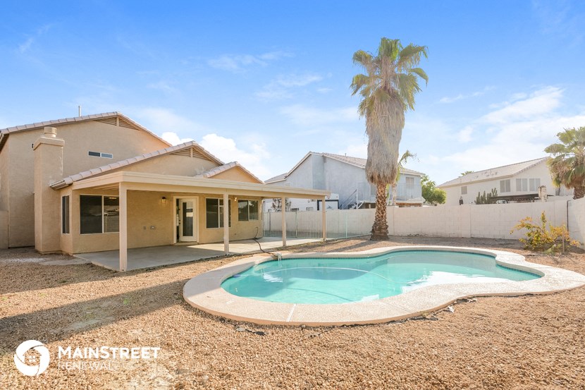 a backyard with a pool and a house with a palm tree