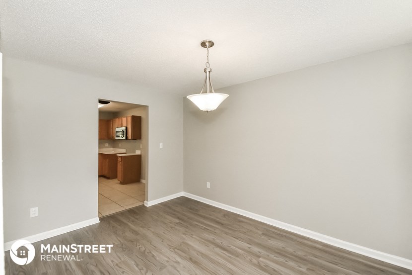 a spacious living room with wood flooring and a chandelier