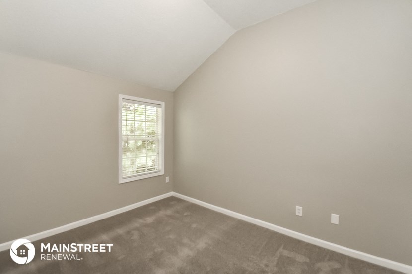 the upstairs bedroom has a carpeted floor and a window