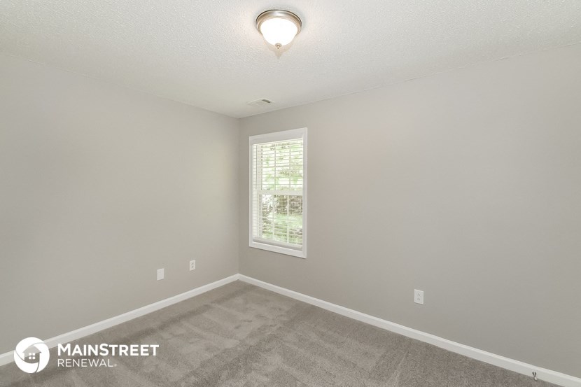 the spacious living room with carpeted flooring and a window