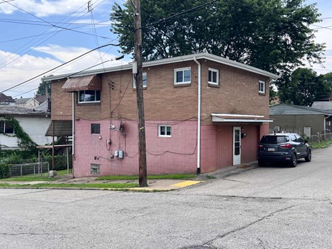 A pink building with a car parked in front.