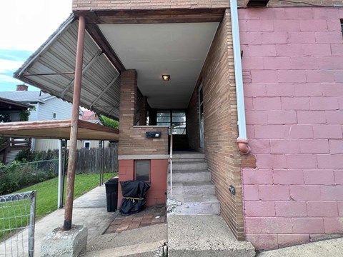 A pink building with a covered walkway leading to the front door.