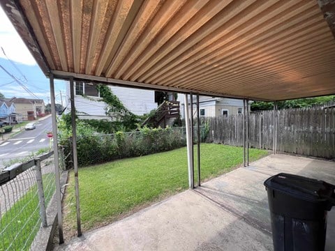 A patio with a trash bin and a fence.