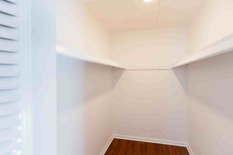 A long, narrow hallway with white walls and wooden flooring.