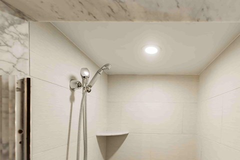 A shower head with a hose attached is mounted on a wall.