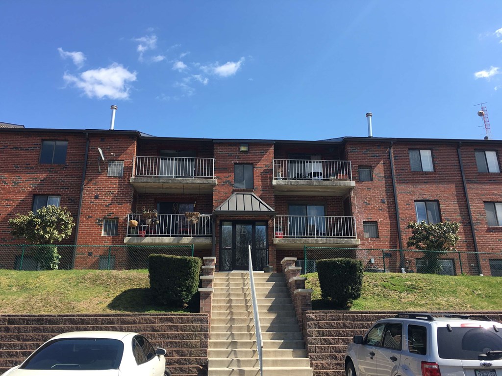 an apartment building with stairs and cars parked in front