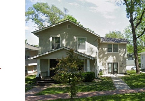 A two-story house with a front porch and a tree in front.