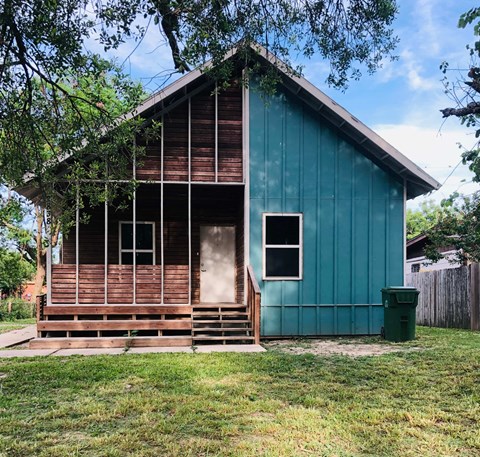 a small cabin with a wooden porch and a green house