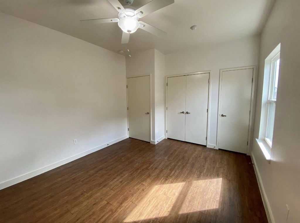 an empty living room with wood floors and a ceiling fan