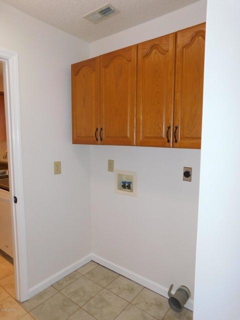 A kitchen with wooden cabinets and a white wall.