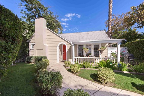 a small white house with a red front door and a yard with a walkway