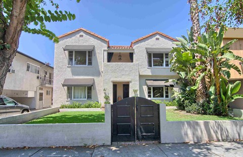 a white house with a black gate in front of a yard
