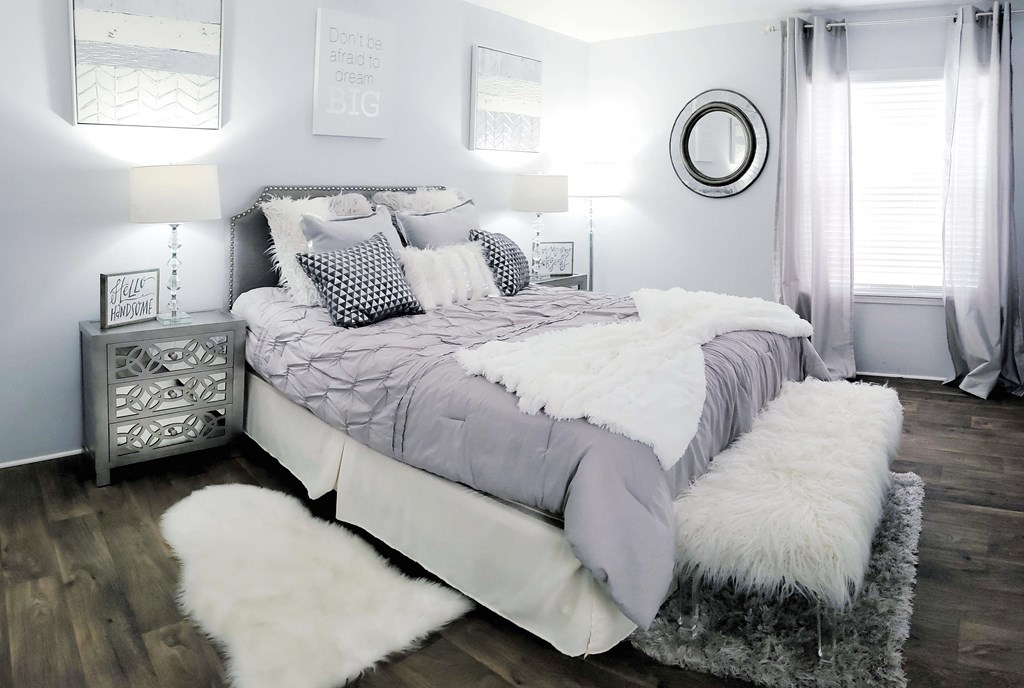 a gray and white bedroom with a bed and white furry rug