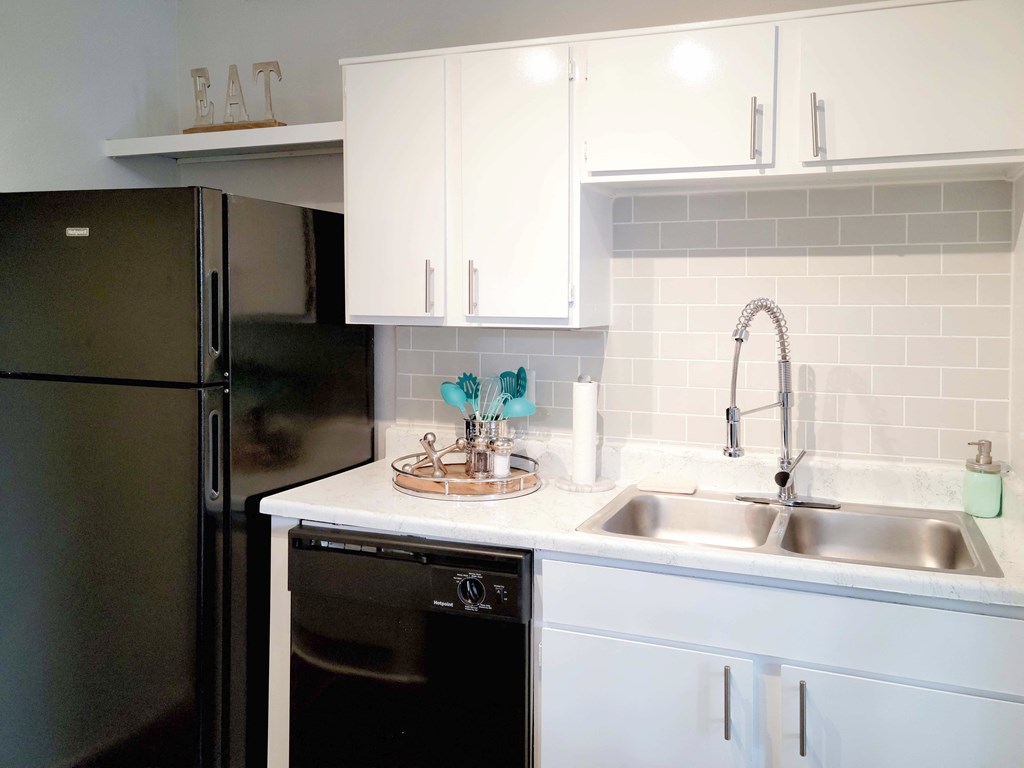 a kitchen with white cabinets and a sink and a refrigerator
