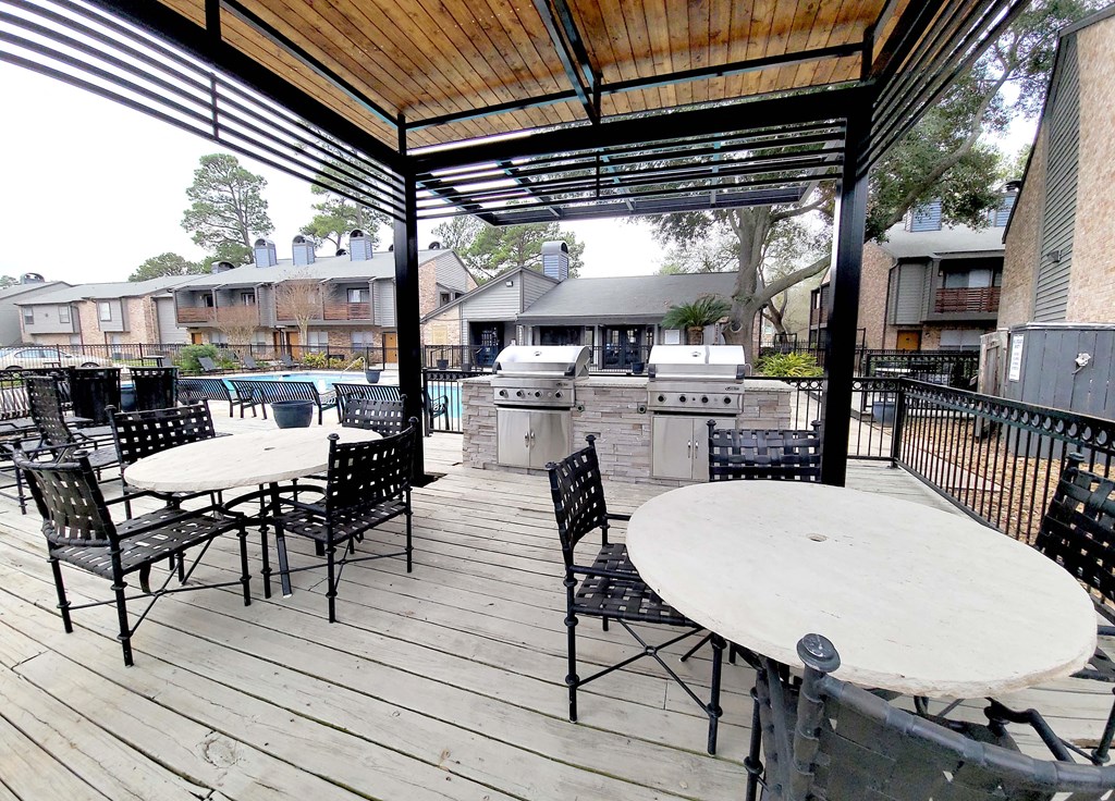 a covered patio with tables and chairs and a grill