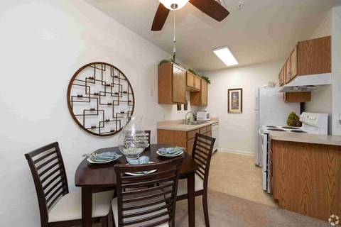 A dining room with a table set for two and a ceiling fan.