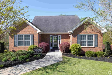 A brick house with a sign in front.