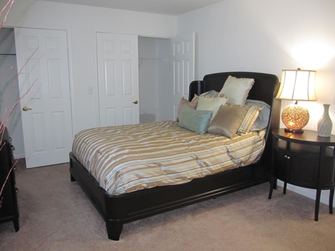 A bedroom with a bed, nightstand, and two doors.