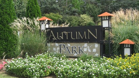 A sign that says Autumn Park in front of some trees.