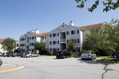 A parking lot in front of a large white apartment building.