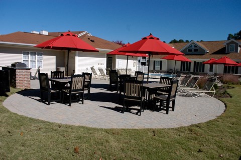 A patio with red umbrellas and chairs.