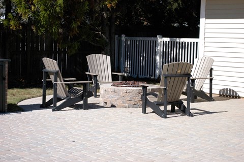 Three chairs and a table are on a patio.