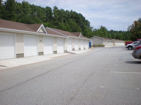 A parking lot with a few cars and a building in the background.