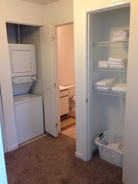 A laundry room with a washer and dryer and a closet with shelves.