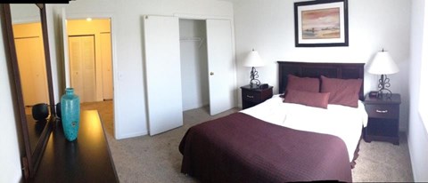 A bedroom with a large bed and a painting on the wall.